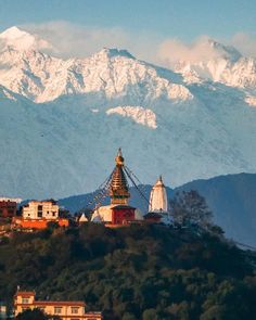 the mountains are covered in snow and there is a building on top that has a golden roof