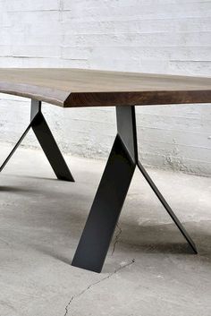 a wooden table with black metal legs and a white brick wall in the back ground