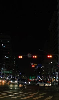 cars are driving through an intersection at night