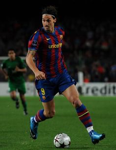 a soccer player is running with the ball in his hand as he looks to kick it