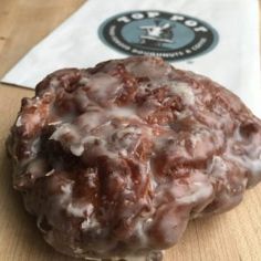 a donut covered in icing sitting on top of a wooden table next to a napkin