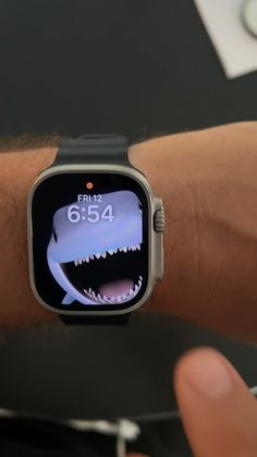 an apple watch with a shark on it's screen showing the time and date