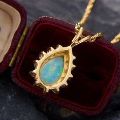 This mesmerizing pendant features a pear cabochon cut opal that is nicely encompassed by a beautiful halo of round brilliant cut diamond accents. The pendant is crafted from 14k yellow gold and hangs from a 24 inch 14k yellow gold rope chain. The opal has some light crazing, but is not very noticeable and does not distract from its great play-of-color. Yellow Gold Teardrop Jewelry With Halo Setting, Yellow Gold Teardrop Halo Jewelry, Formal Opal Teardrop Pendant Jewelry, Formal Teardrop Opal Pendant Jewelry, Gold Pear-shaped Halo Jewelry, Yellow Gold Opal Teardrop Pendant Jewelry, Formal Opal Pear-shaped Jewelry, Pear-shaped Opal Jewelry For Formal Occasions, Formal Pear-shaped Opal Jewelry