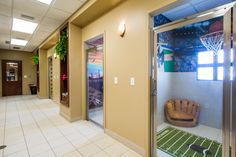 an indoor basketball court is seen through the glass doors in this office building hallway with white tile flooring