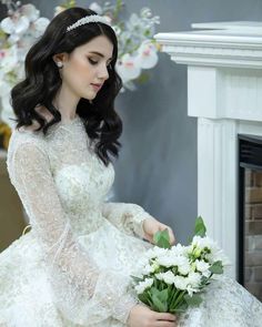 a woman in a white wedding dress sitting on the floor holding a bouquet of flowers