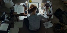 a person sitting at a desk with a laptop and papers on the floor next to them