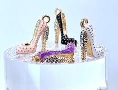 four pairs of high heeled shoes are on top of a clear display case,