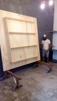 a man standing next to a large wooden cabinet