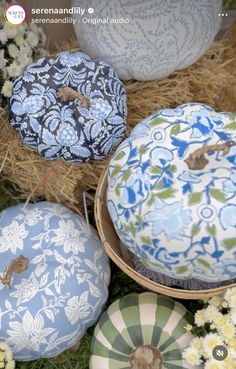 several blue and white ornaments sitting on top of some hay with flowers in the background