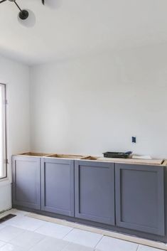 an empty room with gray cabinets in the middle and white tile flooring on the other side