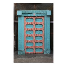 an old blue and pink door with ornate carvings on it's sides, sitting in front of a building