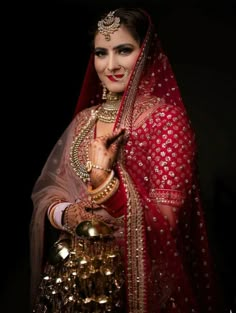 a woman dressed in red and gold with jewelry on her hands, posing for the camera