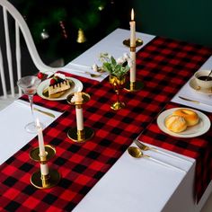 the table is set for christmas dinner with red and black checkered cloth on it