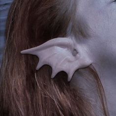 a close up of a person's face with ear clips in the shape of bats