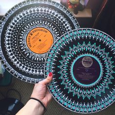 a person holding up two records with designs on the cover and in front of them