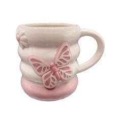 a ceramic cup with a pink butterfly on the top and bottom, sitting in front of a white background