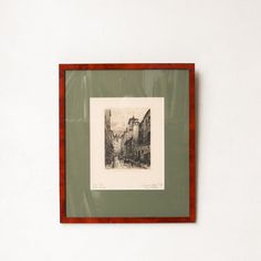 an old photo hanging on the wall in front of a white wall with a red frame