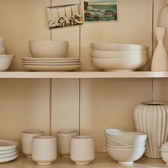 the shelves are filled with white dishes and vases