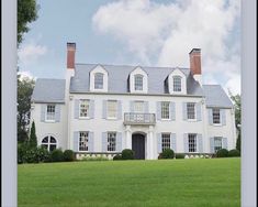 a large white house sitting on top of a lush green field