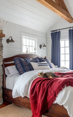 a cat laying on top of a bed in a room with white walls and wood beams