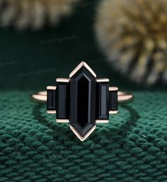 a black stone ring sitting on top of a green cloth