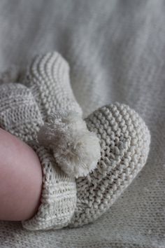 a close up of a baby's foot wearing a knitted hat and mittens