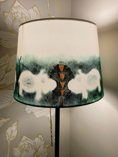 a lamp that is on top of a table next to a flower wallpapered wall