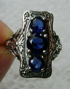 "Simulated Blue Sapphire Ring 3Stone Rectangle#60 Custom Made This is a lovely late Victorian era reproduction ring in solid sterling silver. The gorgeous filigree ring is set with 3 round-cut simulated blue sapphire gemstones. The 2 smaller blue sapphire gems are 4.5mm in diameter, and the center one is 6mm in diameter. This filigree setting is a casting from an actual Antique ring; notice the amazing etched band... The ring sits 3/4th\" (19mm) NS on the finger. The quality of the silver and ge Sterling Silver Sapphire Ring With Rectangular Stone, Sapphire Three Stone Sterling Silver Ring, Blue Three Stone Sapphire Ring In Sterling Silver, Three Stone Sapphire Ring In Sterling Silver, Antique Blue Multi-stone Jewelry, Classic Multi-stone Sapphire Sterling Silver Ring, Antique Silver Three Stone Jewelry, Classic Multi-stone Sapphire Ring In Sterling Silver, Sapphire Three Stone Ring Jewelry