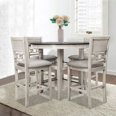 a dining room table with four chairs and a vase on top of it in front of a window