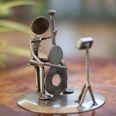 a metal figurine sitting on top of a wooden table next to a wrench