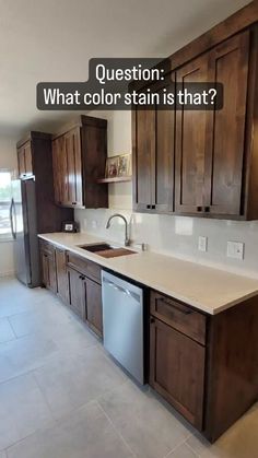 an empty kitchen with brown cabinets and white counter tops is featured in the article question what color stain is that?