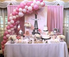 a table topped with lots of pink and white balloons next to a tall eiffel tower