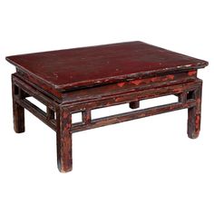 an old wooden coffee table with red paint on the top and two small stools underneath it