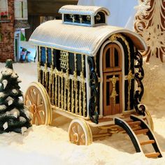 a toy horse drawn carriage sitting in the snow next to a christmas tree and other decorations