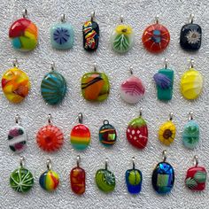 many different colored glass pendants on a white tablecloth with one being an ornament