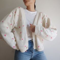 a woman wearing a white cardigan with pink hearts on it