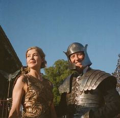 a man and woman dressed in armor standing next to each other on a sunny day