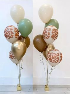 giraffe print balloons are arranged in front of a white wall with gold and green accents