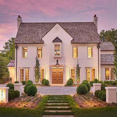 a white house with steps leading up to it's front door and windows at dusk