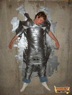 a man is dressed in silver foil and has his arms wrapped around the body of an object