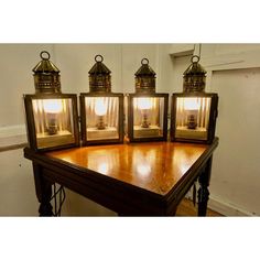 three antique brass lanterns sitting on top of a wooden table