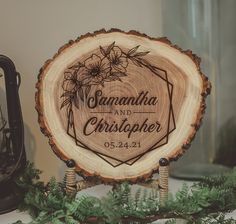 a wooden sign that says savannah and christopher on it next to some greenery in front of a lantern