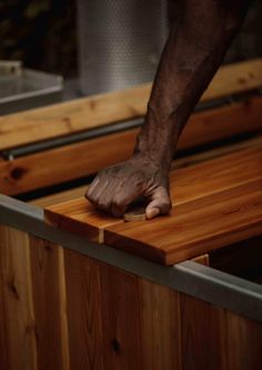 a man's hand on the edge of a wooden counter top with metal bars