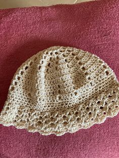 a crocheted hat sitting on top of a pink blanket