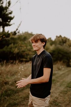 a young man standing in a field with his hands out