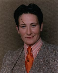 a woman in a suit and orange tie