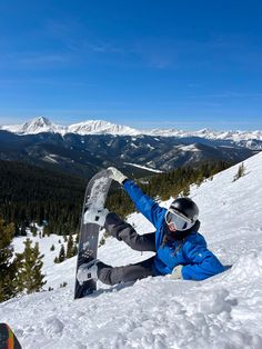 a snowboarder is sitting in the snow with his board on their feet and arms out