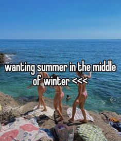 two women in bikinis standing on rocks near the ocean with text saying wanting summer in the middle of winter > >