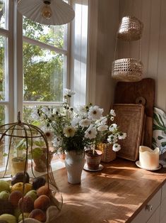 a kitchen counter topped with lots of flowers and fruit next to a window sill