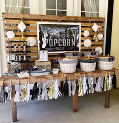 a wooden table topped with lots of baskets filled with food and desserts next to a sign that says popcorn bar